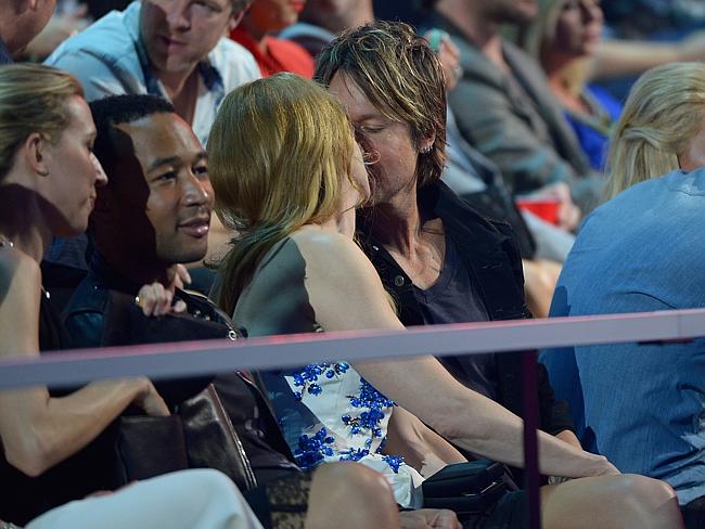Get a room ... Nicole Kidman and Keith Urban share an unguarded kiss as they watch from t