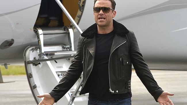 I’m back baby: Robbie Williams greets the media on the tarmac at Perth Airport. Pictures: