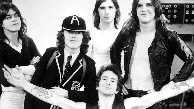 ACDC with leader singer, Bon Scott kneeling flanked by fellow band members Phil Rudd, Mal