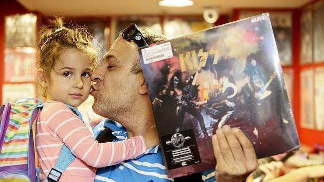 Simona, 3, gets a kiss from her dad Sasa Kajkut as he holds a Kiss album at Red Eye Recor